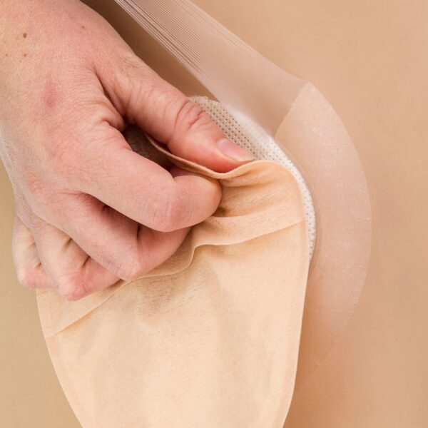 UltraFrame Flange Extenders on someone's skin and a hand pulling the flange showing the elasticity and see through of the flange