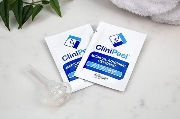 Two CliniPeel wipes next to a CliniSure Urinary Sheath on a marble countertop