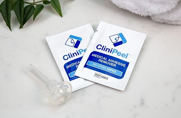 Two CliniPeel wipes next to a CliniSure Urinary Sheath on a marble countertop