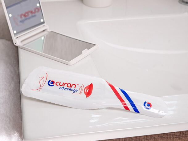 Curan advantage female catheter on a bathroom sink with a mirror and towel.