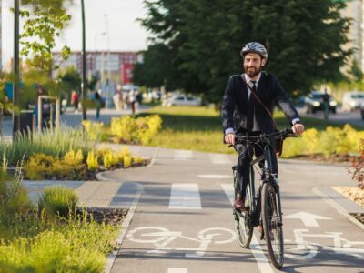 Man on a bicycle cycling along a green space cycle path