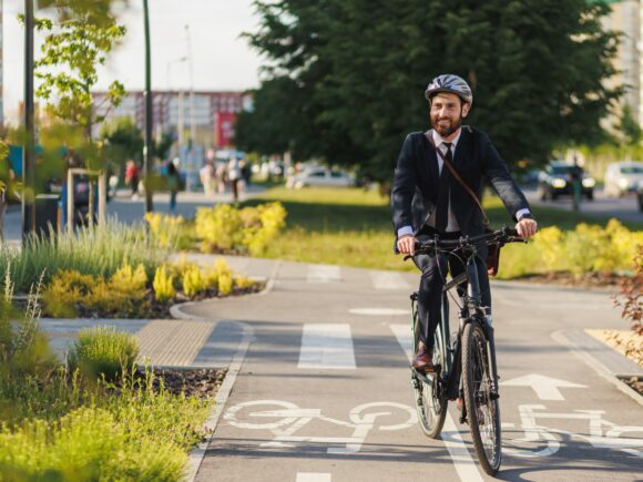Man on a bicycle cycling along a green space cycle path
