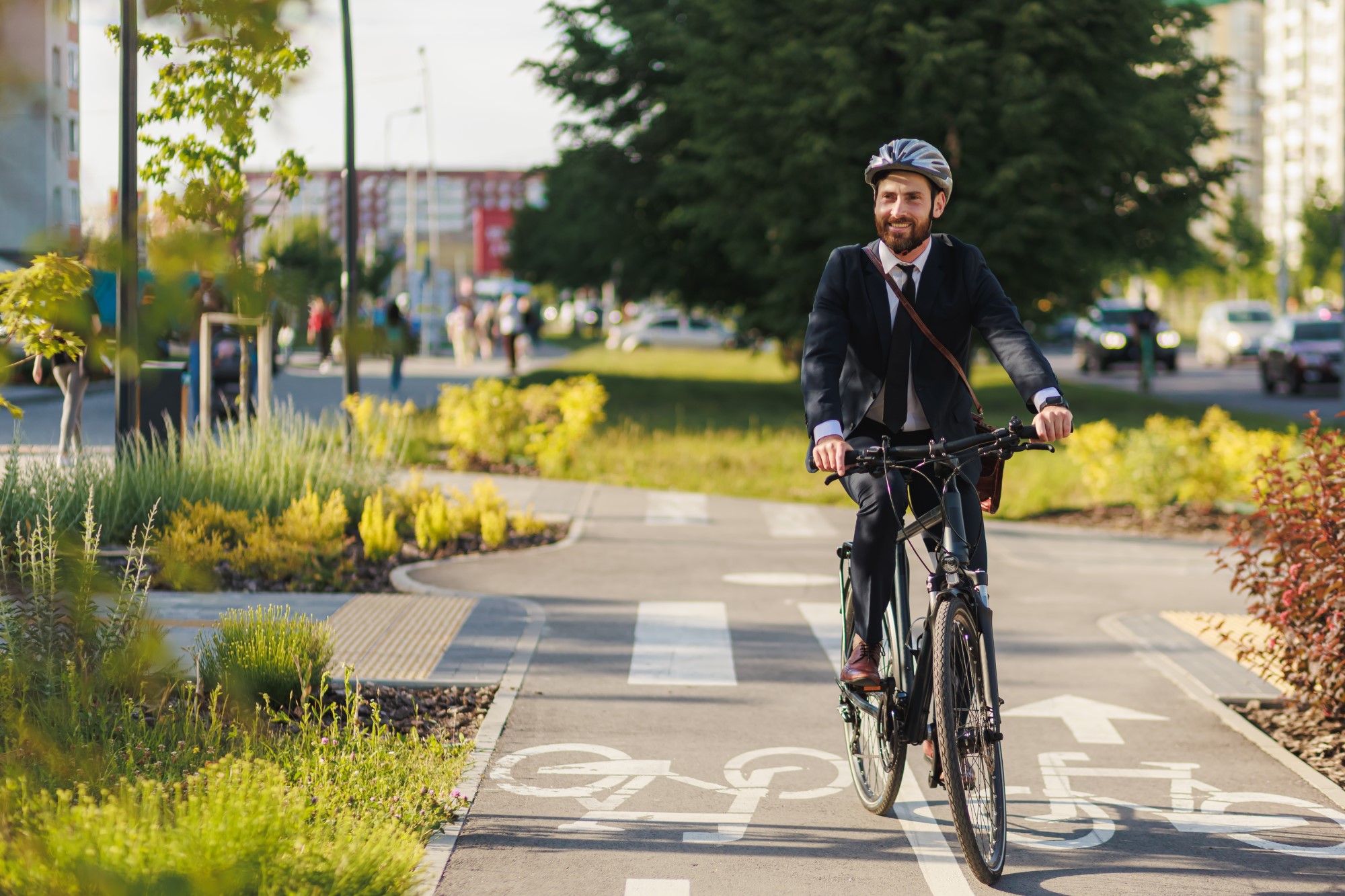 Man on a bicycle cycling along a green space cycle path