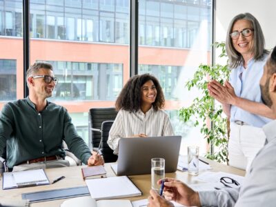 A group of people in a conference room having a meeting and smiling.