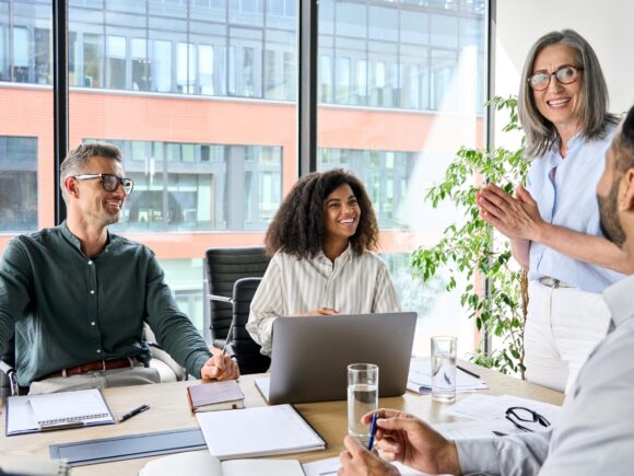 A group of people in a conference room having a meeting and smiling.