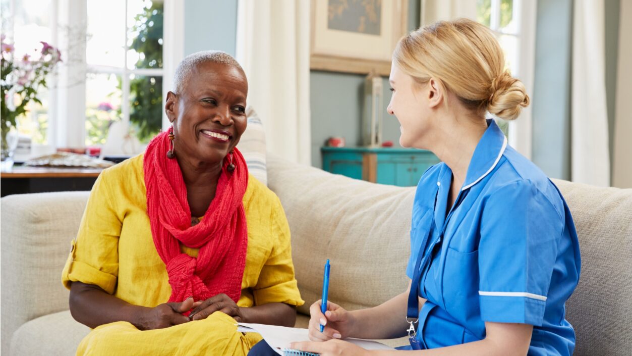 nurse sitting on a sofa chatting with a patient