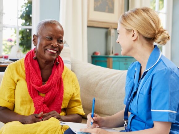 nurse sitting on a sofa chatting with a patient