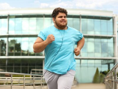 A plus-sized young man who is jogging in an urban setting.