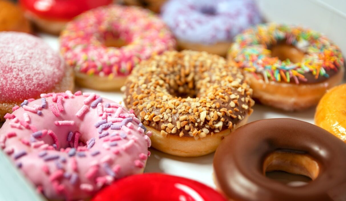 A selection of glazed and sprinkled doughnuts in a box.