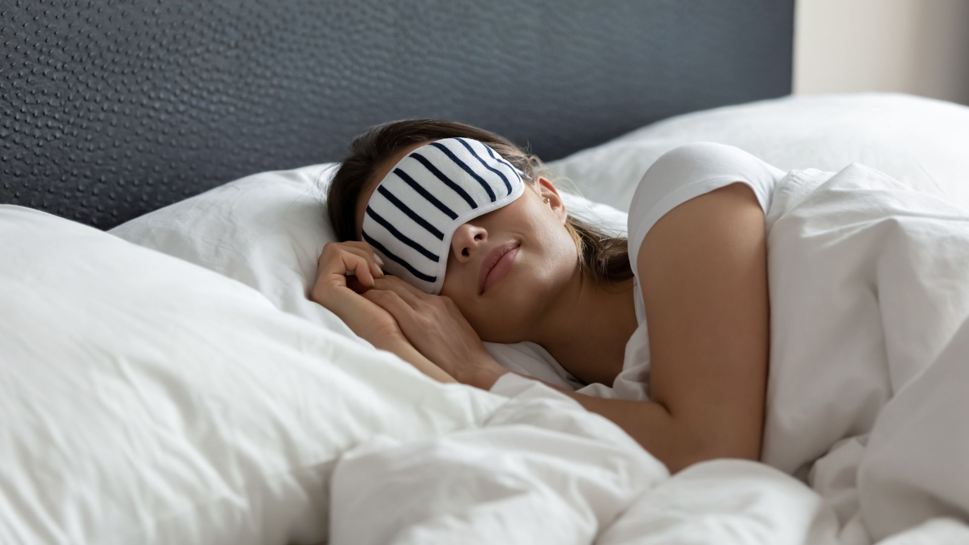 Young woman in bed sleeping wearing an eye mask