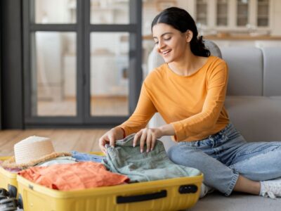 Photo of a lady sat on her floor packing her suitcase.