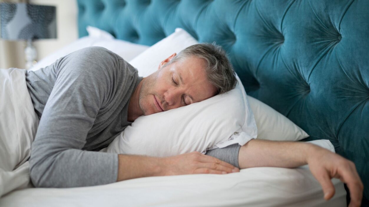 Photo of a man sleeping in bed wearing pyjamas.