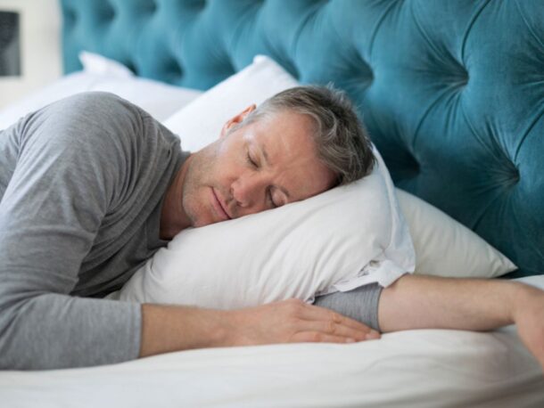 Photo of a man sleeping in bed wearing pyjamas.