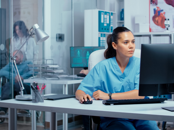 Photo of a nurse looking at a computer screen.
