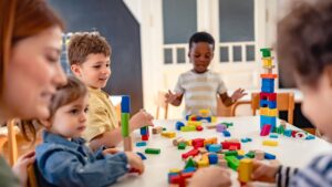 Photo of children sitting around a table playing with building blocks.