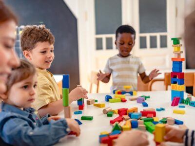 Photo of children sitting around a table playing with building blocks.