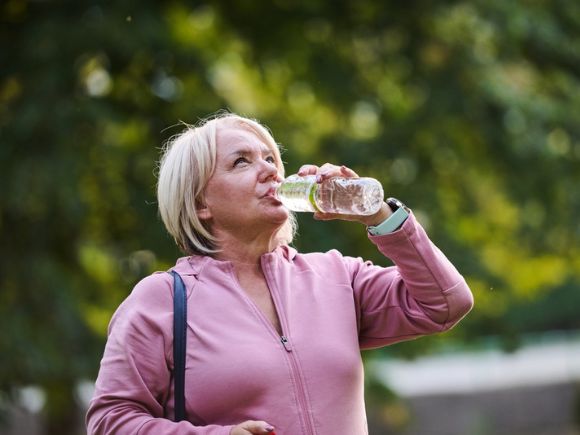 Lady drinking water from a bottle whilst outside