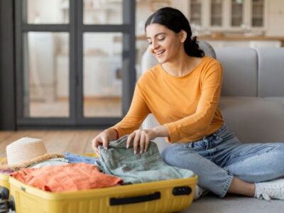 Photo of a lady sat on her floor packing her suitcase.