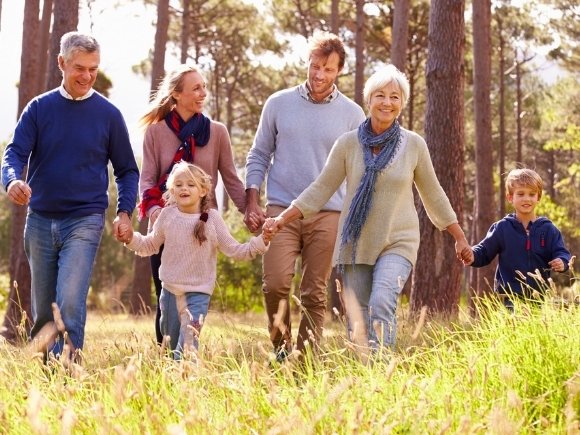 Photo of a family walking together through a field holding hands.