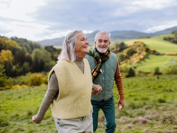 Photo of a man and woman holding hands outside in a field