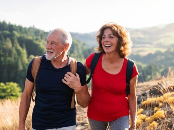 Photo of a man and women linking arms walking through a field together