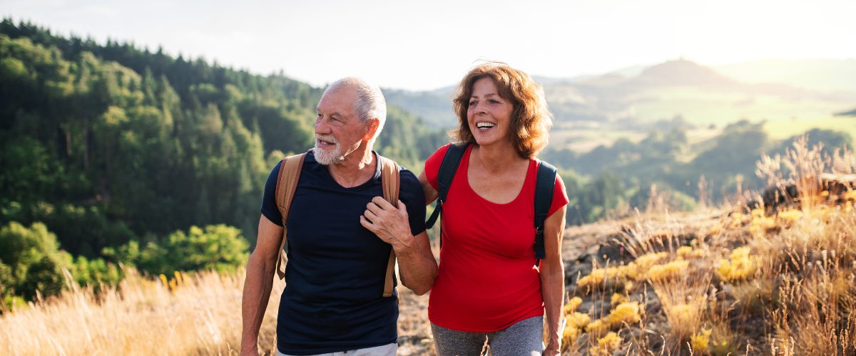 Photo of a man and women linking arms walking through a field together