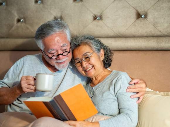 Image of a couple sat in bed reading a book together