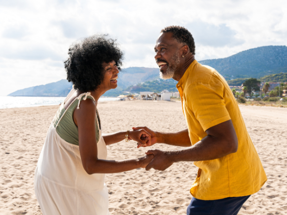 Image of a couple holding hands smiling together on a beach