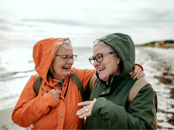 Photo of two older women talking a walk on the beach together