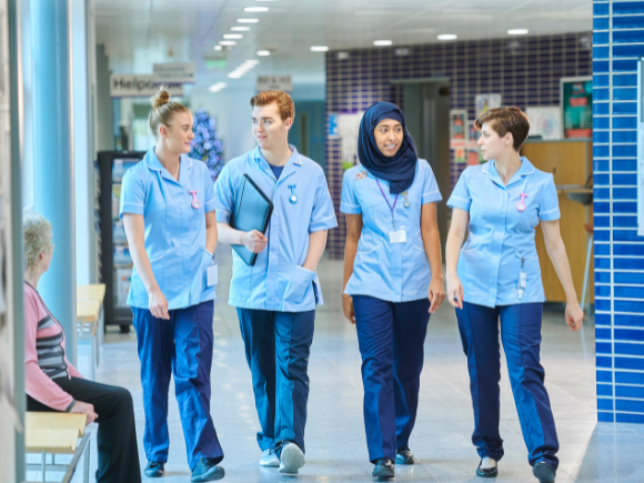 Group of healthcare professionals walking through a hospital corridor.