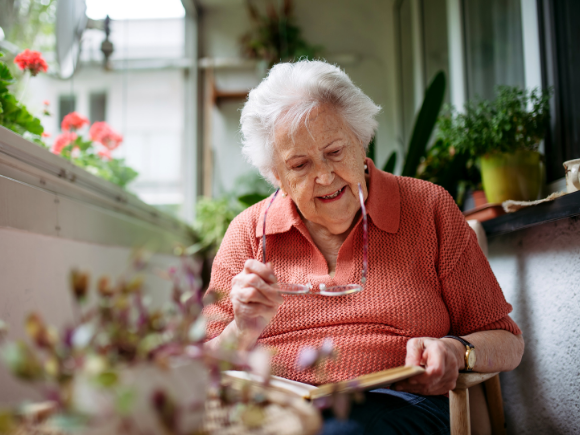 Image of an elderly lady sitting down in a garden reading