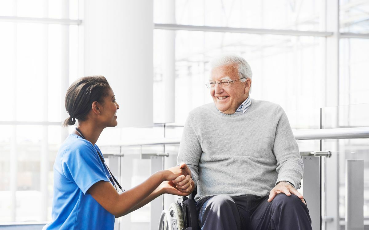 nurse with man in wheelchair smiling